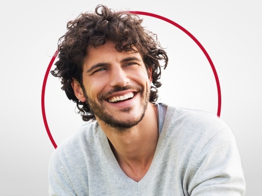 Smilende ung mand i grå bluse, der er glad efter Canesten® behandling mod svamp