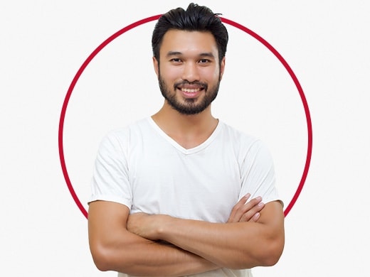 Smilende ung mand i grå t-shirt, der står selvsikkert og er glad efter en Canesten® behandling mod lyskesvamp