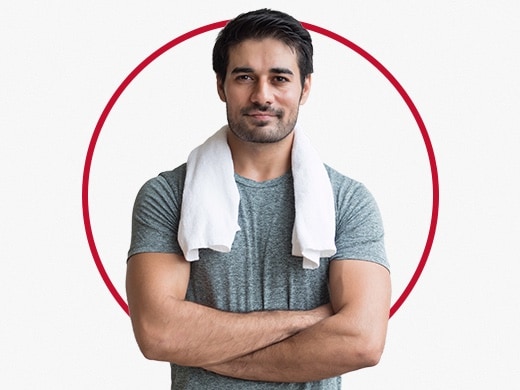 Muskuløs mand med hvidt håndklæde om halsen, der er glad efter Canesten® behandling mod rødme i hudfolder