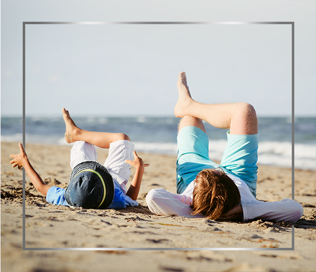 Mor og barn, der ligger på stranden med krydsede ben og er glade efter en Canesten® behandling med svampeinfektion i huden